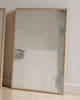 Two wooden-framed mirrors leaning against a light-colored wall.