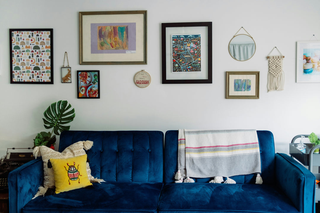 blue velvet couch in front of an eclectic gallery wall. 