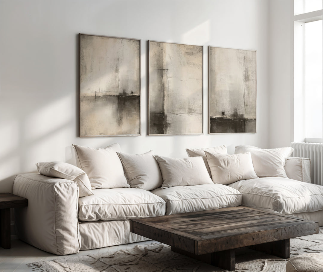 set of 3 abstract neutral prints in frames above a sofa in a living room, neutral interior design style with prints which have beige, brown, charcoal and warm nude tones