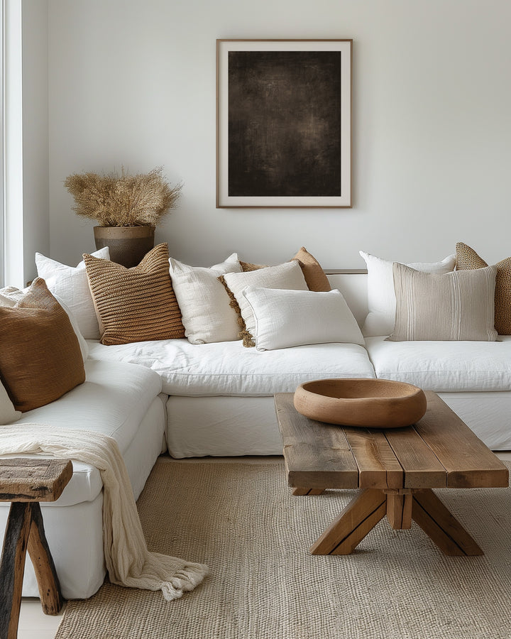 Cosy living room with a white sectional sofa, wooden coffee table, and decorative pillows, the focal point of the wall is a brown neutral print framed with a mount added